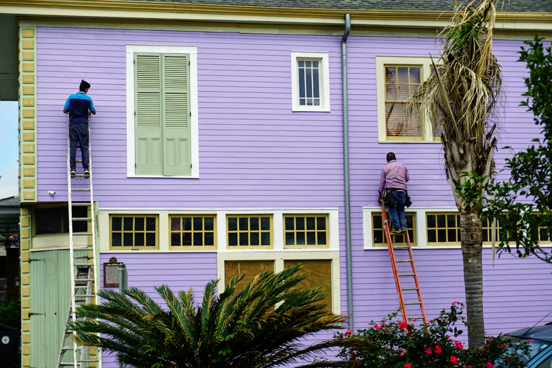 Painters on ladders painting a home exterior